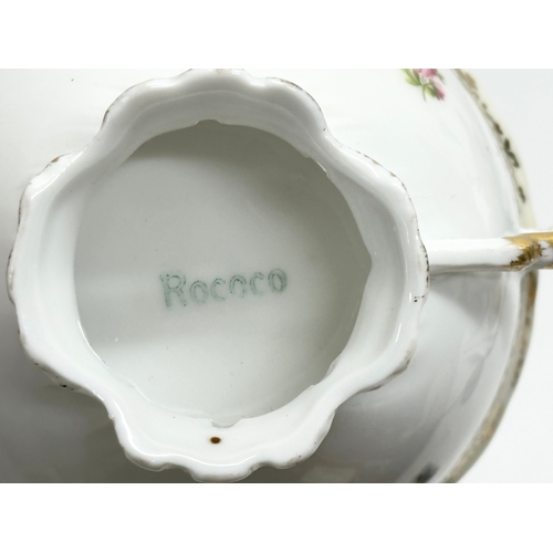 253 - A pair of Early 20th Century Rococo hand painted cups and saucers.