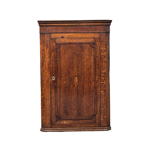 1171 - A George III inlaid oak wall hanging corner cabinet with fitted shelves. Circa 1790-1800. 69.5x38.5x... 