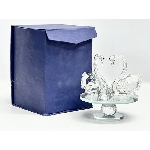 557 - A pair of crystal swans on rotating base. With box. 15x15x17cm