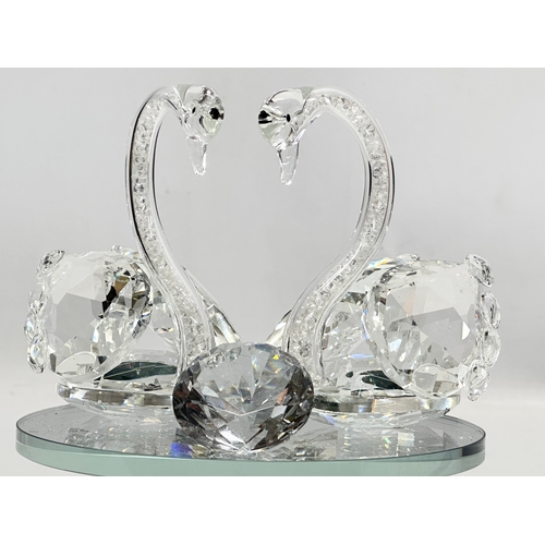 557 - A pair of crystal swans on rotating base. With box. 15x15x17cm