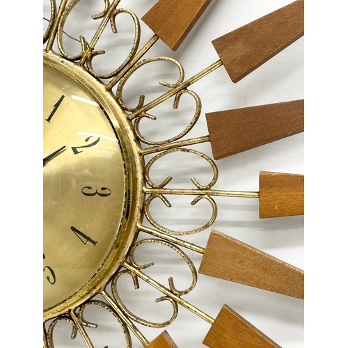 137 - A 1960’s Mid Century teak sunburst clock by Paico. 52cm