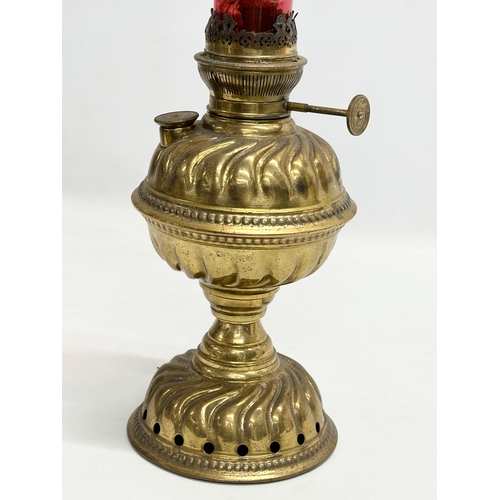 151 - A Late 19th Century brass oil lamp with later ruby glass shade. 39cm