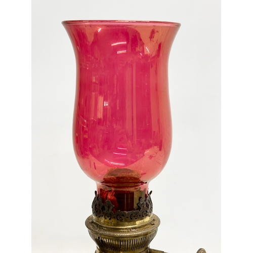 151 - A Late 19th Century brass oil lamp with later ruby glass shade. 39cm