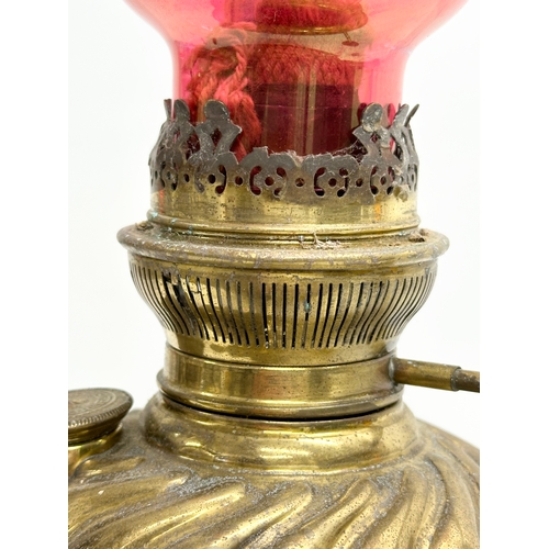 151 - A Late 19th Century brass oil lamp with later ruby glass shade. 39cm