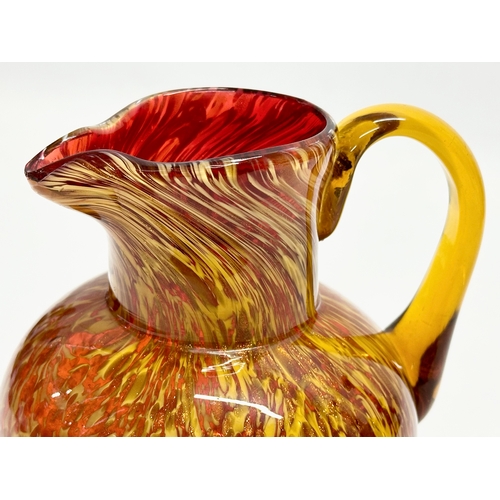 81 - An Early 20th Century art glass jug with gold mica flakes on a ruby ground, and amber glass handle. ... 