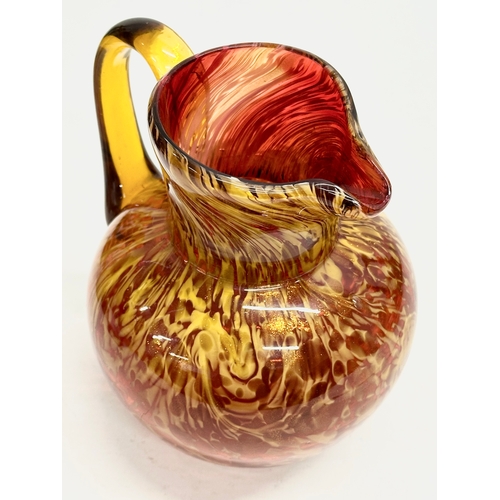 81 - An Early 20th Century art glass jug with gold mica flakes on a ruby ground, and amber glass handle. ... 