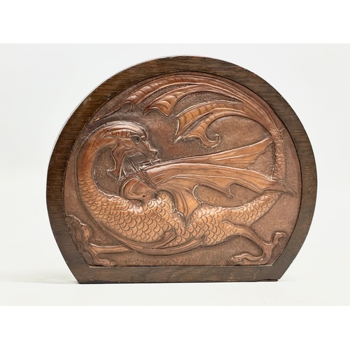 32 - A pair of Late 19th/ Early 20th Century bookends with embossed dragon leather panels in oak frames a... 