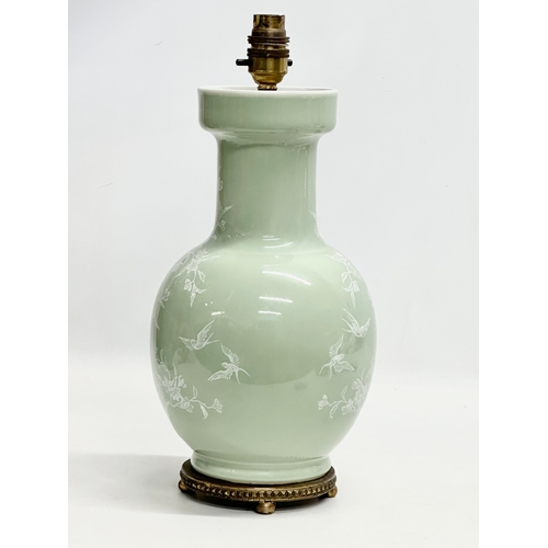 102 - A Chinese Celadon glazed table lamp with brass base. Decorated with white prunus leaves and birds in... 