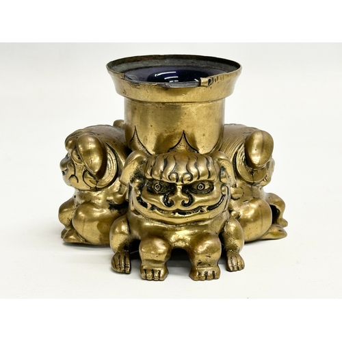 234 - A Late 19th Century brass foo dog ink well with Bristol Blue liner. 11.5x8.5cm.