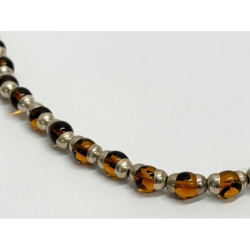 655 - A large silver and amber glass necklace.