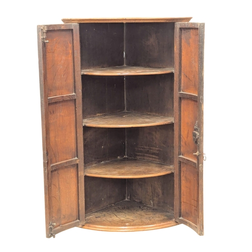 912 - A Late 18th Century George III oak wall hanging corner cupboard with fitted shelves. 65x46x107cm(7)