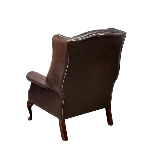 864 - A Mid 20th Century Georgian style leather wingback armchair. On Queen Anne legs.(10)