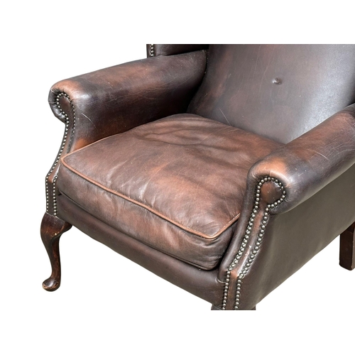 864 - A Mid 20th Century Georgian style leather wingback armchair. On Queen Anne legs.(10)