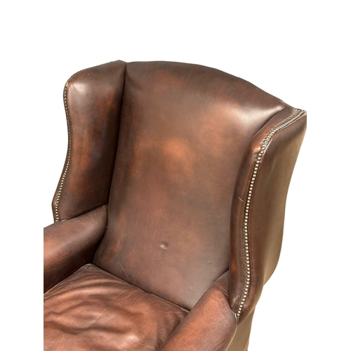 864 - A Mid 20th Century Georgian style leather wingback armchair. On Queen Anne legs.(10)