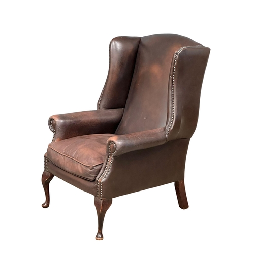 864 - A Mid 20th Century Georgian style leather wingback armchair. On Queen Anne legs.(10)