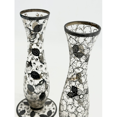 157 - A near pair of Early 20th Century glass vases with hand painted silver overlay. 23cm