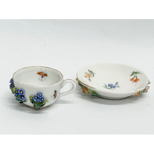 20 - A Late 19th/Early 20th Century, Sitzendorf miniature cup and saucer. Hand painted, with encrusted fl... 