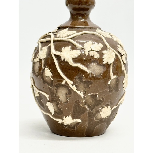 838 - An 18th Century glazed stoneware bottle, with moulded relief vines and leaves. 11x18cm