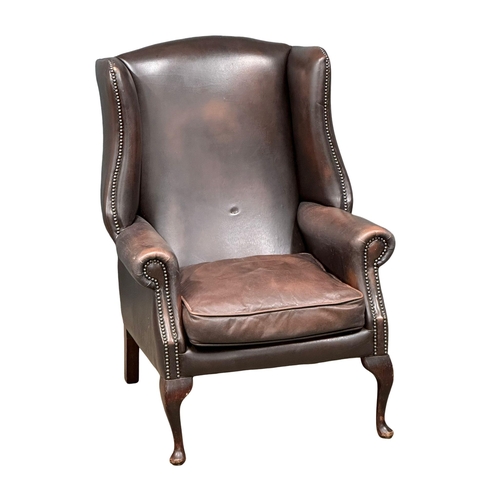 609 - A Mid 20th Century Georgian style leather wingback armchair. On Queen Anne legs.(10)