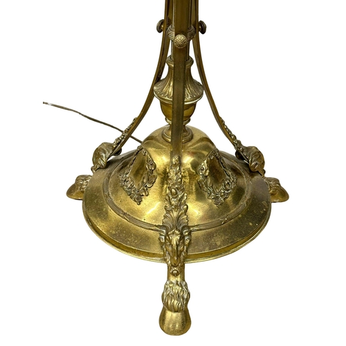 70 - A large good quality Early 20th Century brass standard lamp., with rams head decoration on hairy hoo... 