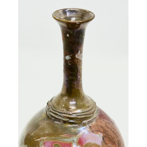 405 - A signed studio pottery bottle vase. With iridescent lustre glazed over terracotta. 23cm