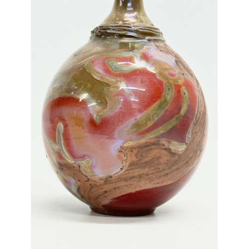 405 - A signed studio pottery bottle vase. With iridescent lustre glazed over terracotta. 23cm