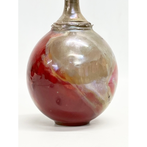 405 - A signed studio pottery bottle vase. With iridescent lustre glazed over terracotta. 23cm