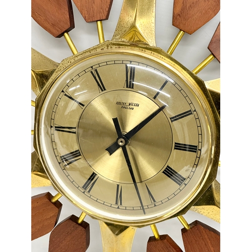 143 - Anstey & Wilson. A 1960’s Mid Century teak and brass sunburst clock. 43x48cm