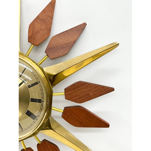 143 - Anstey & Wilson. A 1960’s Mid Century teak and brass sunburst clock. 43x48cm