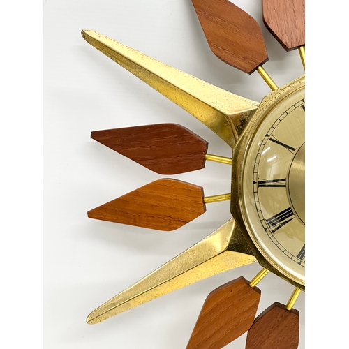 143 - Anstey & Wilson. A 1960’s Mid Century teak and brass sunburst clock. 43x48cm