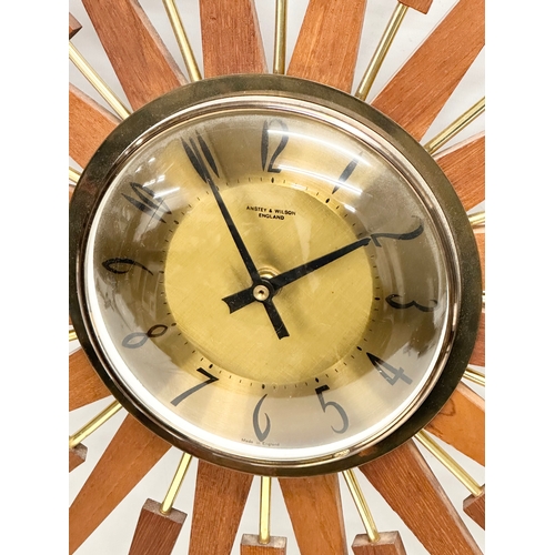 94 - Anstey & Wilson. A large 1960’s Mid Century teak sunburst clock. 63x63cm