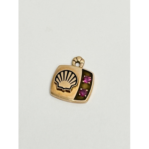 679 - A 10k gold pendant with garnets and shell logo. 2.95 grams.