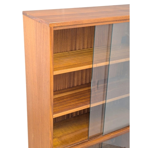 921 - A Mid Century teak bookcase with 4 sliding glass doors. 69x28x144cm (4)