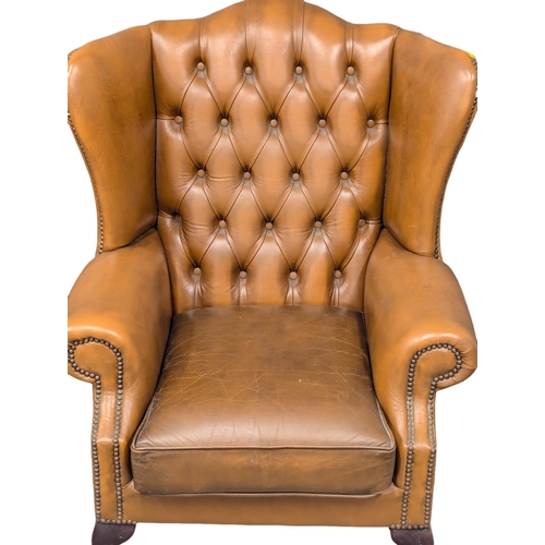 193 - A Georgian style deep button leather wingback armchair.