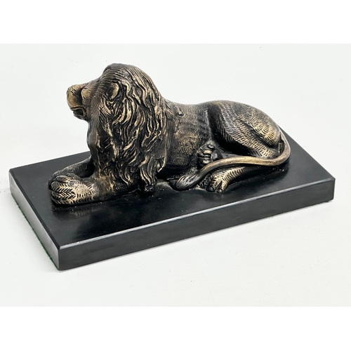 462 - A brass lion on slate base. 23.5x11.5x13cm