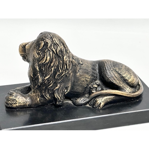 462 - A brass lion on slate base. 23.5x11.5x13cm