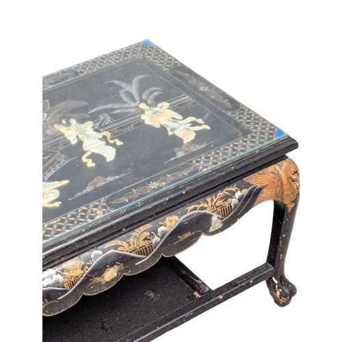 904 - An Oriental lacquered glass top coffee table with Mother of Pearl figures. 104x54x44cm