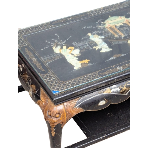 904 - An Oriental lacquered glass top coffee table with Mother of Pearl figures. 104x54x44cm