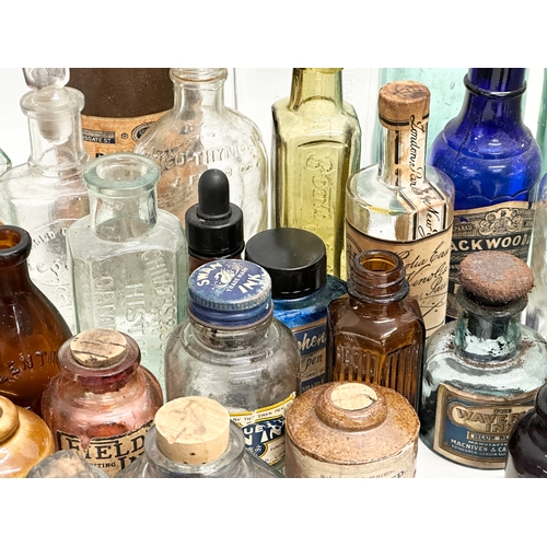 523 - A large collection of 19th and 20th Century glass bottles and jars. Chemist, ink, whiskey etc.