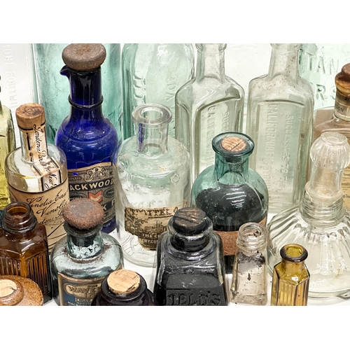 523 - A large collection of 19th and 20th Century glass bottles and jars. Chemist, ink, whiskey etc.