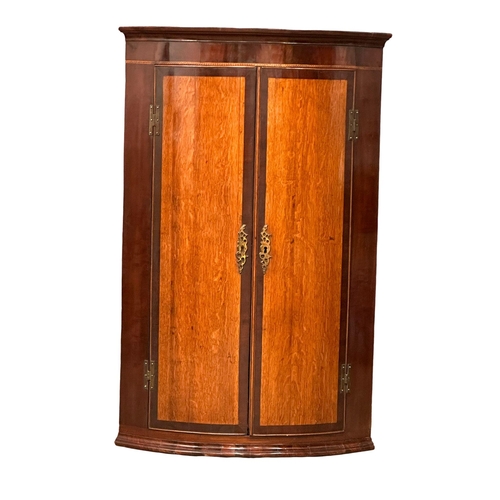 386 - A Late 18th Century George III inlaid mahogany wall hanging corner cupboard, with oak panel doors an... 