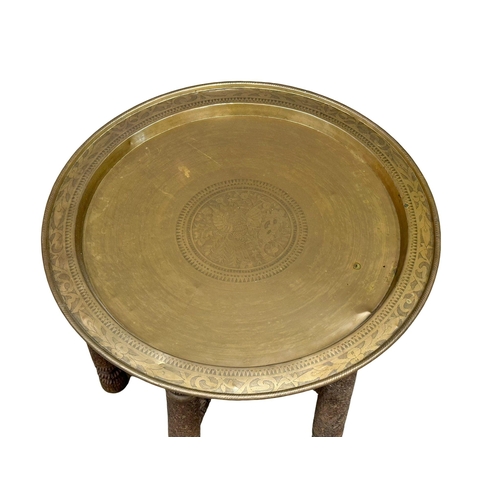 424 - A Late 19th Century Burmese carved teak folding table with brass tray top. 62x51cm