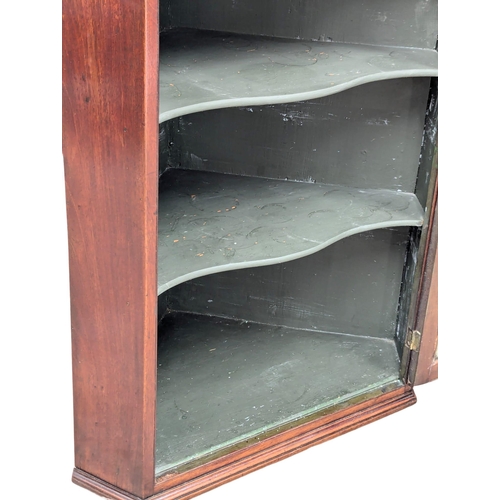 810 - A George III mahogany wall hanging corner cabinet with astragal glazed doors and fitted shelves. 74x... 