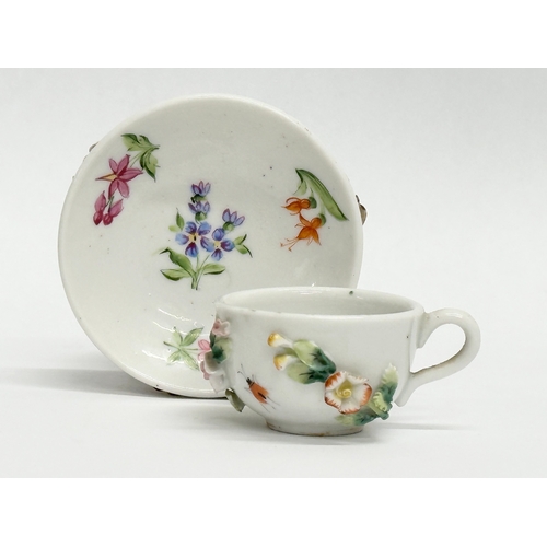 141 - Sitzendorf. A Late 19th/Early 20th Century German flower encrusted miniature cup and saucer, with pa... 