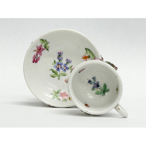 141 - Sitzendorf. A Late 19th/Early 20th Century German flower encrusted miniature cup and saucer, with pa... 