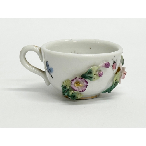 141 - Sitzendorf. A Late 19th/Early 20th Century German flower encrusted miniature cup and saucer, with pa... 