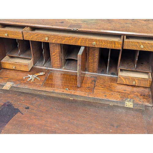 229 - An Early 19th Century George III oak bureau with brass bun handles and bracket feet. Circa 1800. 97x... 