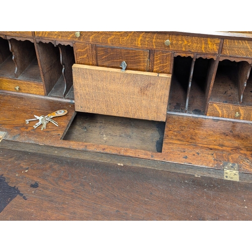 229 - An Early 19th Century George III oak bureau with brass bun handles and bracket feet. Circa 1800. 97x... 