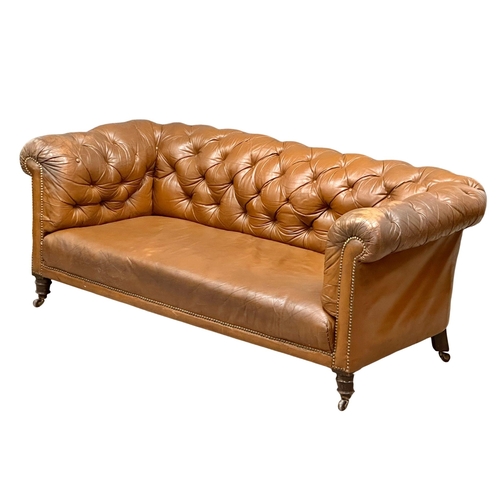 4 - A 19th Century Victorian deep button leather Chesterfield sofa, on turned mahogany legs. Circa 1880.... 