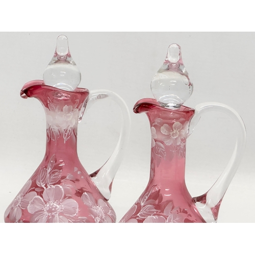 465 - A pair of Early 20th Century painted cranberry glass cruets. 17cm